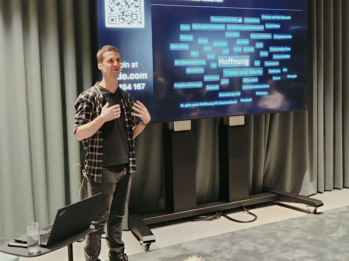 Marc Bernath bei einer Keynote vor einer Leinwand mit einer Wortwolke aus Antworten des Publikums