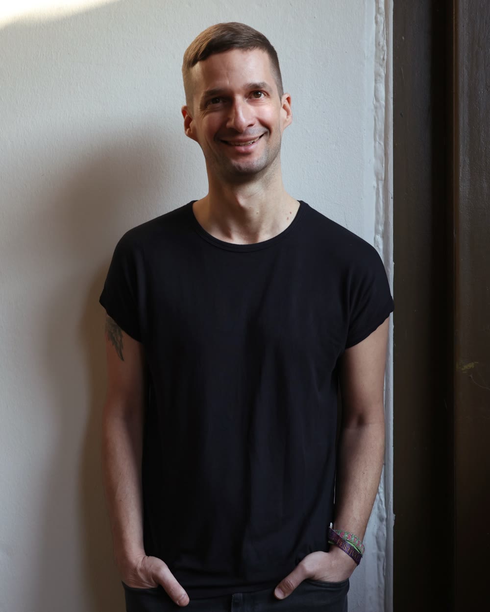 Porträt von Marc Bernath, lächelnd vor einer hellen Wand